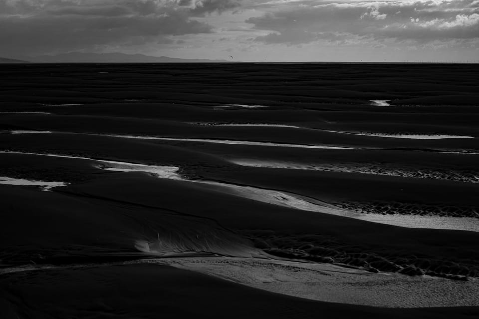 Curved patterns in the sand as the tide has gone out with a view out to North Wales